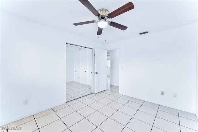unfurnished bedroom with a closet, light tile patterned flooring, a ceiling fan, and baseboards
