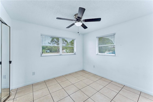 unfurnished bedroom with a textured ceiling, ceiling fan, light tile patterned floors, and baseboards