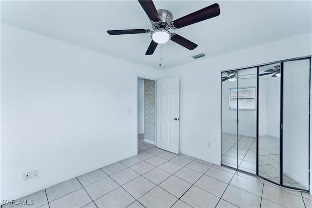 unfurnished bedroom featuring light tile patterned floors, baseboards, ceiling fan, and a closet