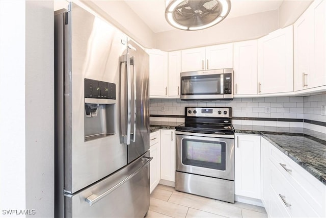 kitchen with dark stone counters, light tile patterned flooring, decorative backsplash, white cabinets, and appliances with stainless steel finishes