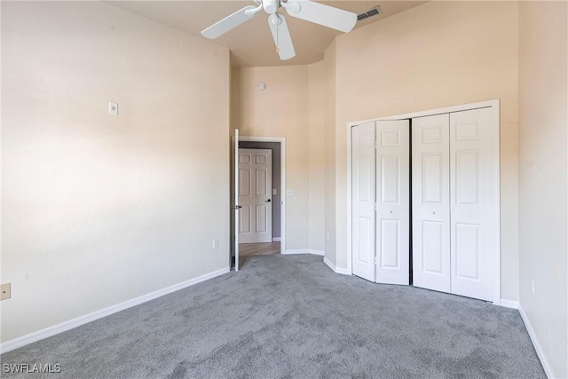 unfurnished bedroom with baseboards, visible vents, carpet, and a towering ceiling