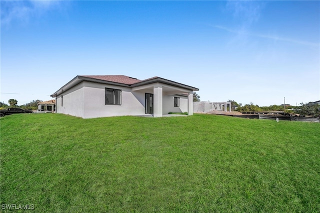 rear view of house with a yard and stucco siding