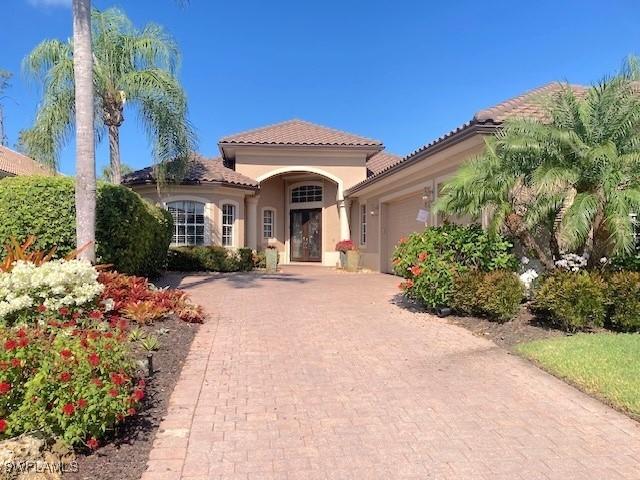mediterranean / spanish house featuring an attached garage, stucco siding, decorative driveway, and a tiled roof