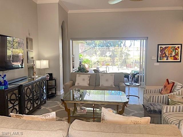 living area with crown molding, arched walkways, baseboards, and wood finished floors