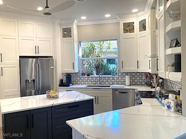 kitchen featuring stainless steel appliances, a sink, white cabinetry, decorative backsplash, and crown molding