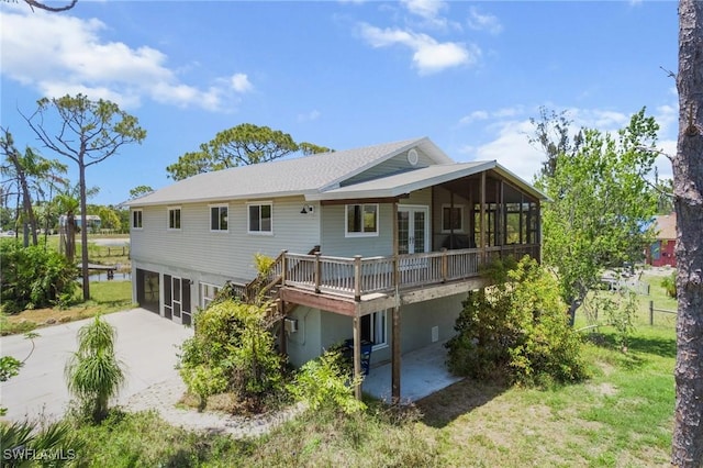 8625 Redwood Dr, Saint James City, FL 33956 - rear view of property with a sunroom, a deck, concrete driveway, a garage, and french doors