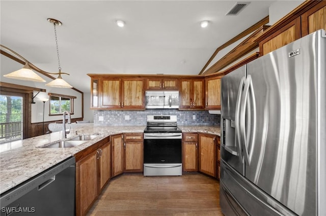 8625 Redwood Dr, Saint James City, FL 33956 - kitchen featuring stainless steel appliances, a sink, brown cabinets, wood finished floors, and lofted ceiling