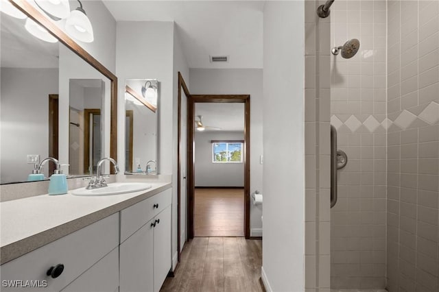 8625 Redwood Dr, Saint James City, FL 33956 - bathroom featuring wood finished floors, tiled shower, vanity, and ceiling fan