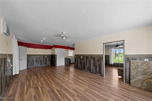 8625 Redwood Dr, Saint James City, FL 33956 - unfurnished living room featuring dark wood-type flooring, wainscoting, a ceiling fan, a wall unit AC, and a fireplace