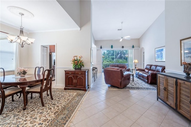 dining area featuring a chandelier, light tile patterned floors, a ceiling fan, arched walkways, and a high ceiling