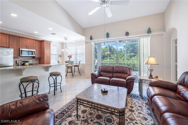 living area featuring a ceiling fan, light tile patterned floors, vaulted ceiling, arched walkways, and recessed lighting