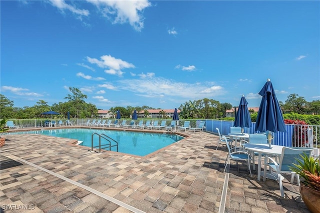 community pool with a patio and fence