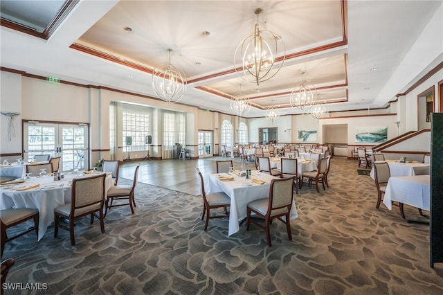 dining space featuring a tray ceiling, a chandelier, ornamental molding, and stone finish flooring