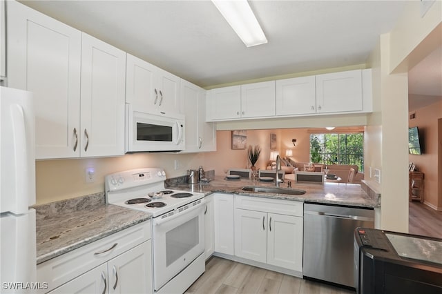 kitchen featuring white appliances, a sink, white cabinetry, light wood-style flooring, and light stone counters