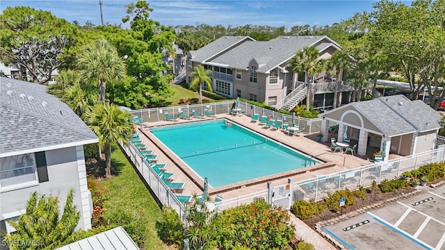 community pool with a fenced backyard, a patio, and view of scattered trees