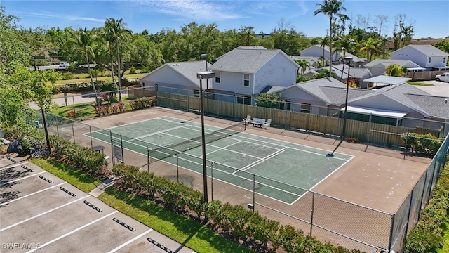 view of tennis court featuring fence and a residential view