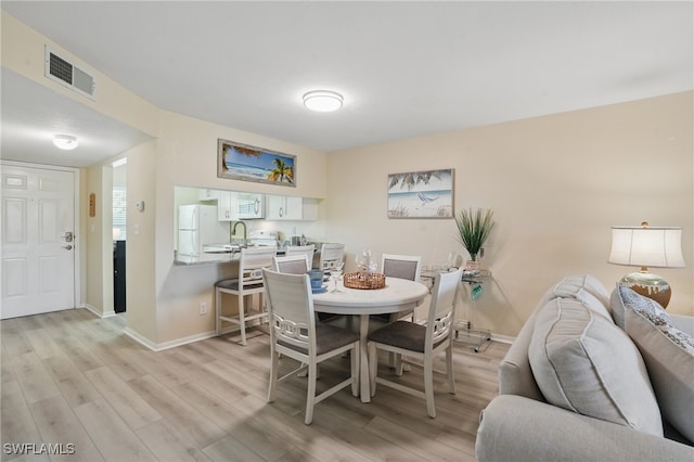 dining area with light wood-type flooring and baseboards