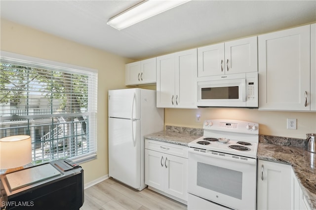 kitchen with white appliances, white cabinetry, light wood-style flooring, and light stone countertops