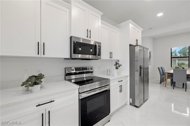 kitchen with appliances with stainless steel finishes, light marble finish floors, recessed lighting, white cabinets, and light stone countertops