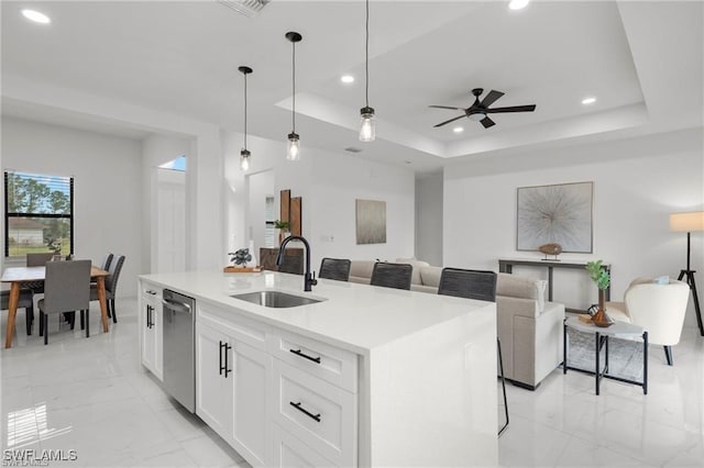 kitchen with a sink, stainless steel dishwasher, recessed lighting, light marble finish flooring, and an island with sink