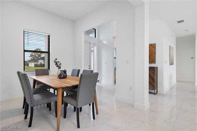 dining space with baseboards and light marble finish flooring