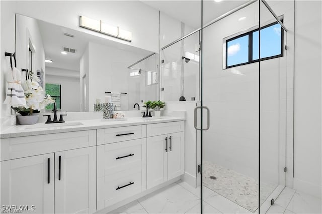 full bath featuring marble finish flooring, a shower stall, and double vanity
