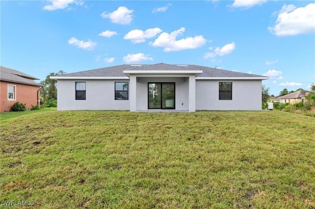rear view of house featuring stucco siding and a lawn