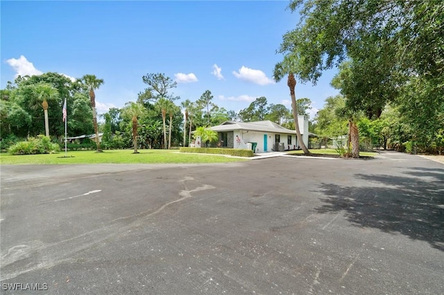 view of front of home with a front yard and view of wooded area