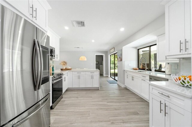 kitchen featuring stainless steel appliances, a peninsula, light countertops, a sink, and recessed lighting