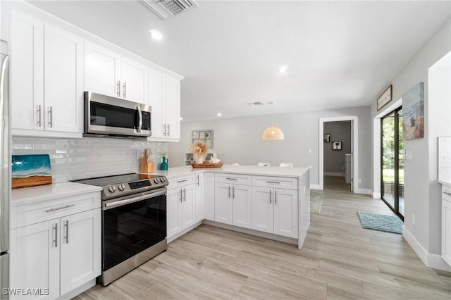 kitchen with stainless steel appliances, a peninsula, tasteful backsplash, light countertops, and white cabinets