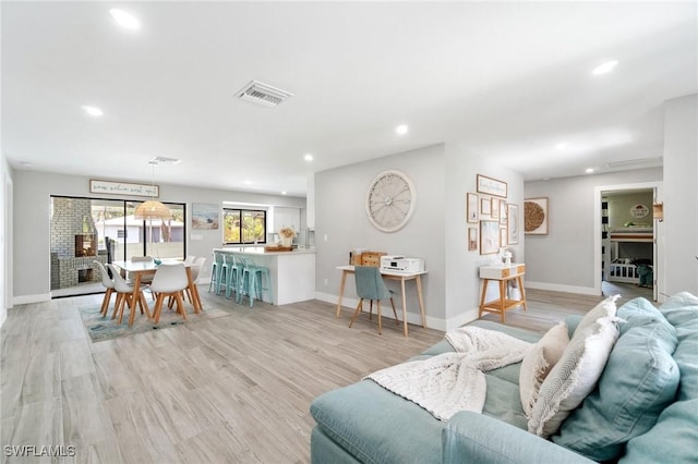 living room with recessed lighting, baseboards, and light wood-type flooring