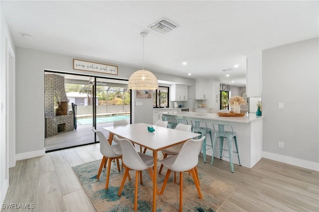 dining area with a fireplace, baseboards, light wood-style floors, and recessed lighting