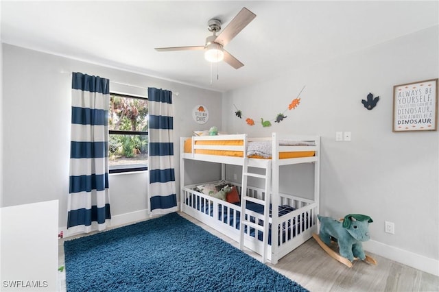 bedroom featuring baseboards, wood finished floors, and ceiling fan