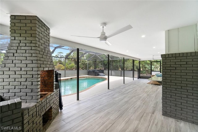 swimming pool featuring a hot tub, a lanai, ceiling fan, and a deck