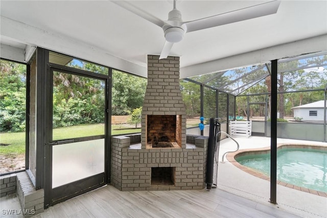 unfurnished sunroom with a fireplace and ceiling fan