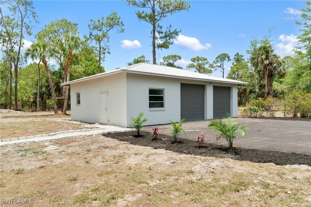 view of side of home featuring a garage, stucco siding, and an outdoor structure