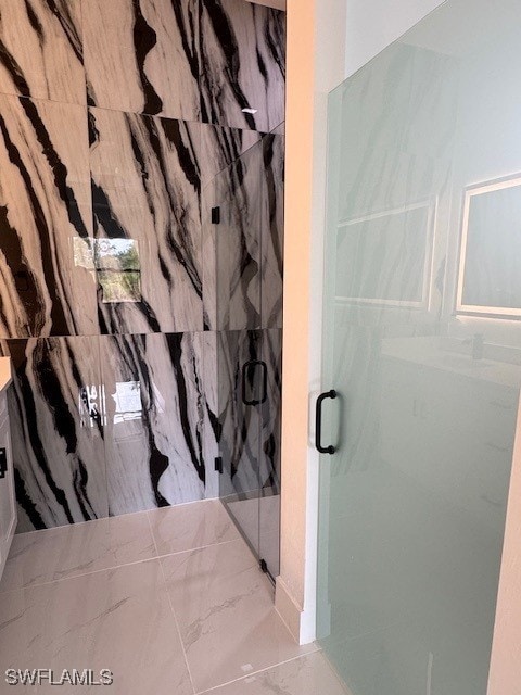 full bath with a marble finish shower and marble finish floor