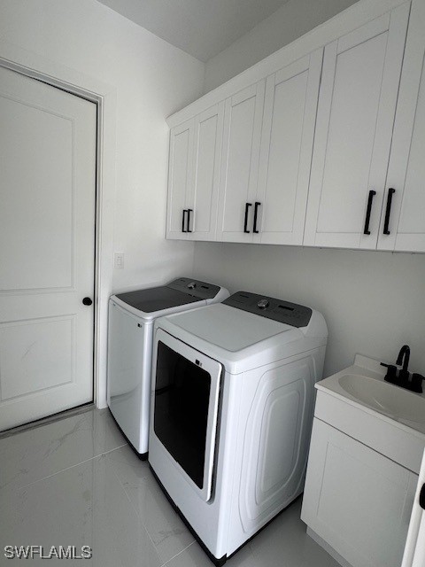 laundry room featuring separate washer and dryer, cabinet space, marble finish floor, and a sink