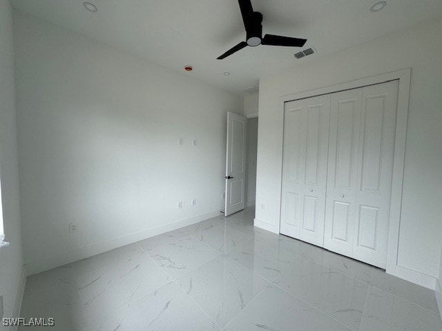 unfurnished bedroom featuring a closet, marble finish floor, visible vents, a ceiling fan, and baseboards