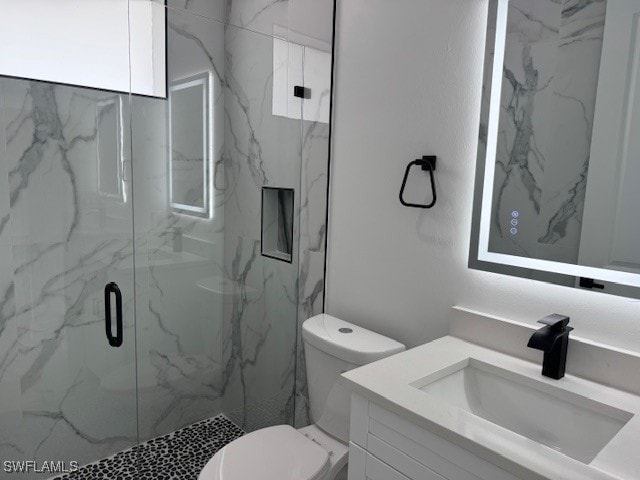 bathroom featuring toilet, vanity, and a marble finish shower