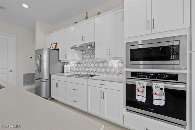 kitchen with under cabinet range hood, appliances with stainless steel finishes, visible vents, and white cabinetry