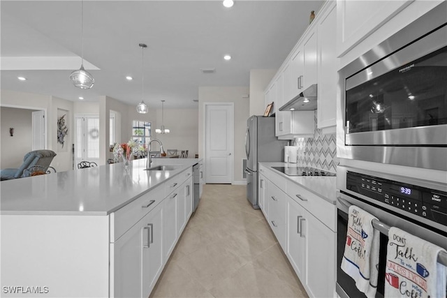 kitchen featuring a sink, stainless steel appliances, under cabinet range hood, light countertops, and decorative backsplash
