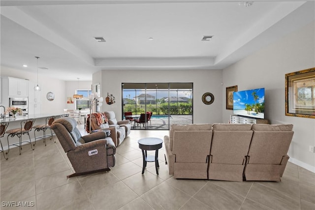 living room featuring a tray ceiling, visible vents, light tile patterned floors, and recessed lighting
