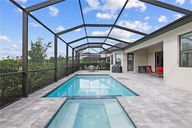 view of pool with a pool with connected hot tub, a patio area, and a lanai