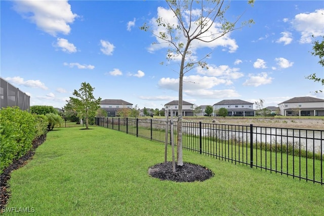 view of yard with fence, a water view, and a residential view