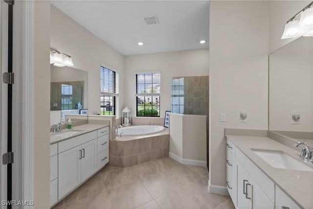 bathroom with a garden tub, two vanities, a sink, and a walk in shower