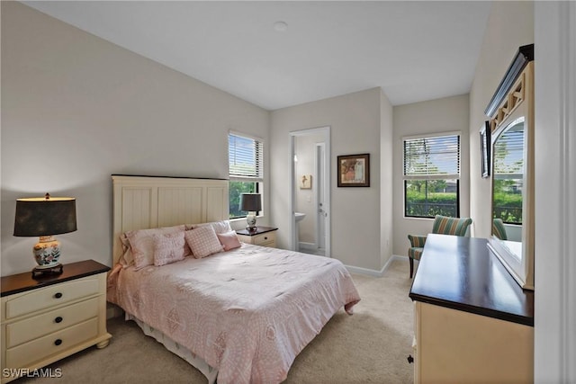 bedroom featuring connected bathroom, light carpet, and baseboards