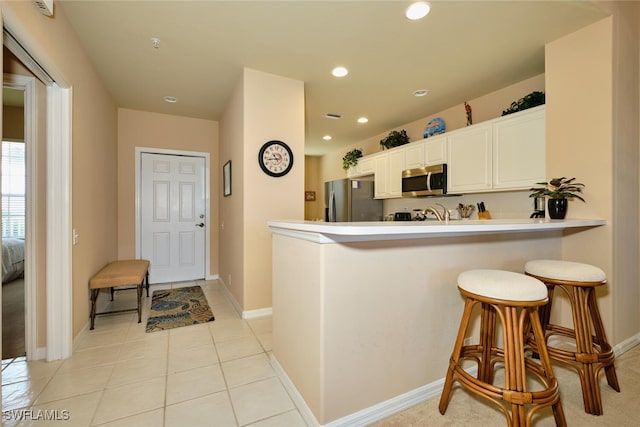 17110 Bridgestone Ct Unit 303, Fort Myers, FL 33908 - kitchen featuring a peninsula, a kitchen bar, stainless steel appliances, white cabinetry, and light countertops