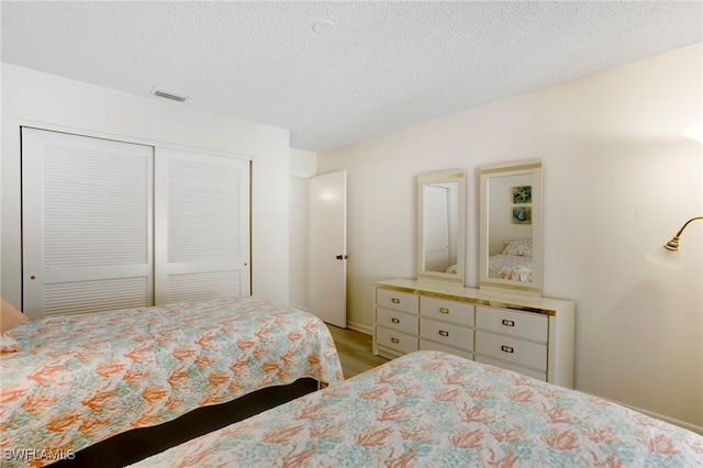 15400 Cedarwood Ln Unit 204, Naples, FL 34110 - bedroom with a closet, wood finished floors, and a textured ceiling