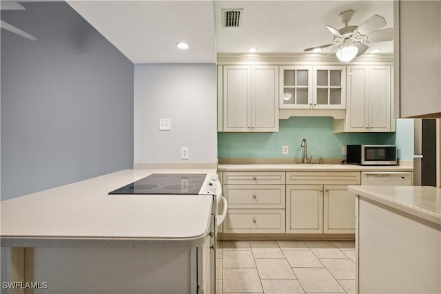 kitchen with stainless steel microwave, a peninsula, a sink, and light countertops